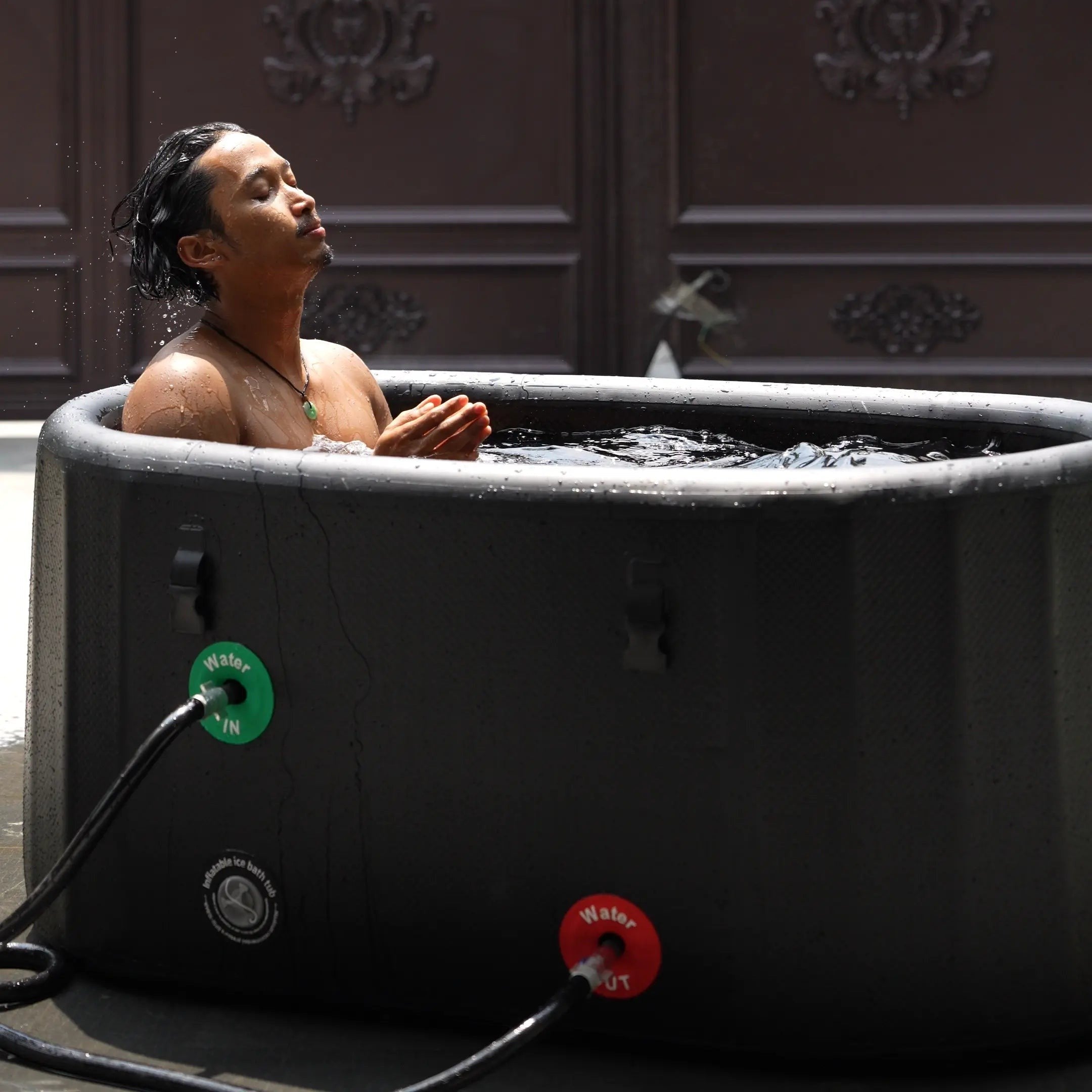 A man is using a Garvnive black PVC ice bath tub for cold therapy recovery; the tub features an air-layered insulation design.